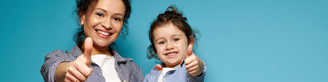 A mother and young daughter giving a thumbs up