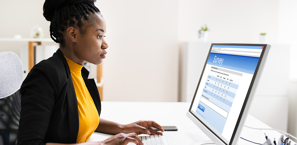 A women sits at a computer completing an online survey