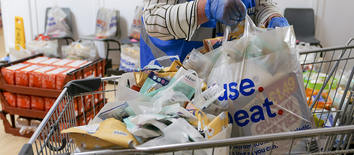 Bags of food being prepared by a volunteer in a charity food bank centre