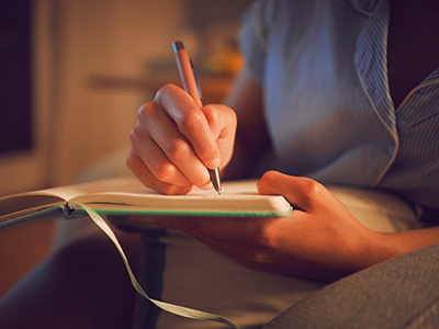 A person writing in a notebook A person writing in a notebook