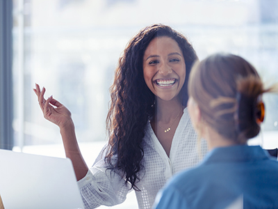 Two female colleagues having a conversation and smiling Two female colleagues having a conversation and smiling