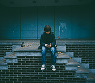 A boy sitting on concrete stairs looking at a mobile phone