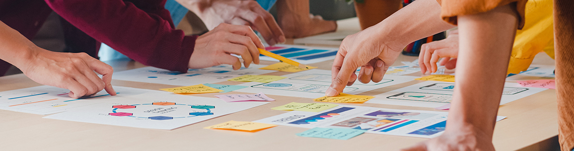 People stood around a table planning a project together. Text